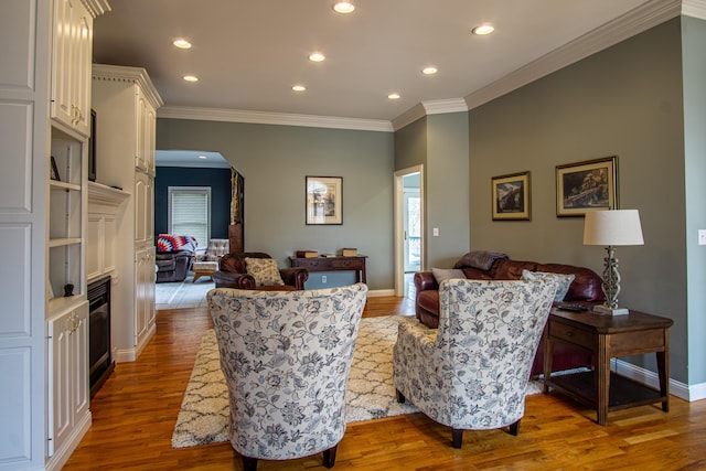 living area featuring arched walkways, crown molding, recessed lighting, wood finished floors, and baseboards