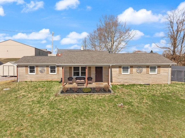 back of house with an outbuilding, roof with shingles, a lawn, a shed, and a patio area