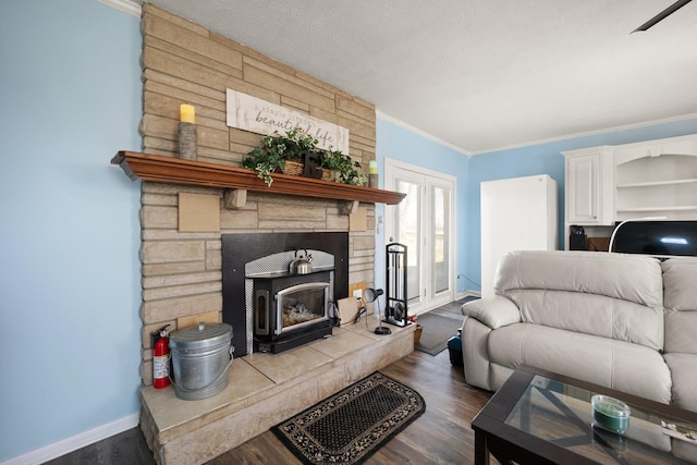 living area with baseboards, dark wood-type flooring, a wood stove, crown molding, and a textured ceiling