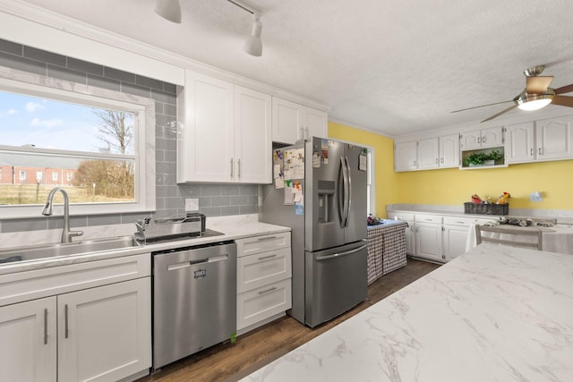 kitchen with appliances with stainless steel finishes, dark wood-style flooring, white cabinets, and a sink