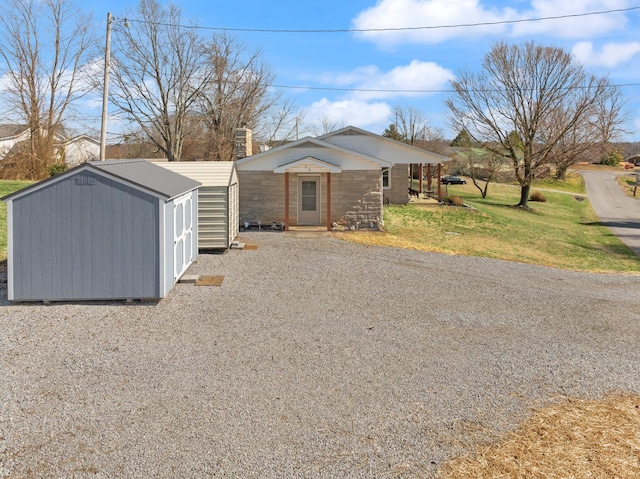 view of front of home with an outbuilding, a chimney, a storage shed, a front yard, and metal roof