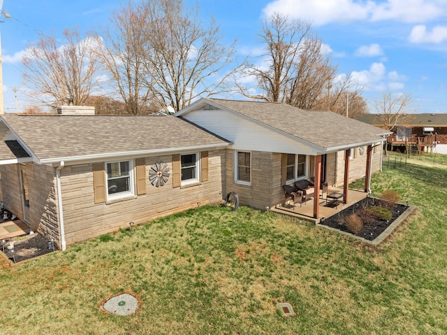 rear view of property with a shingled roof, stone siding, a lawn, and a chimney