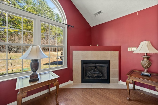 living area featuring lofted ceiling, baseboards, visible vents, and wood finished floors