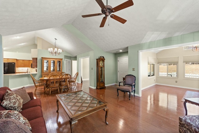 living area with baseboards, wood-type flooring, vaulted ceiling, a textured ceiling, and ceiling fan with notable chandelier