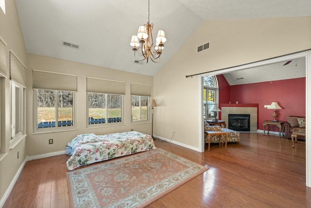 bedroom featuring hardwood / wood-style floors, a tile fireplace, and visible vents