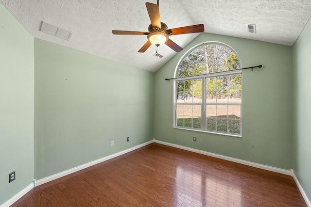 unfurnished room with hardwood / wood-style flooring, baseboards, visible vents, and vaulted ceiling