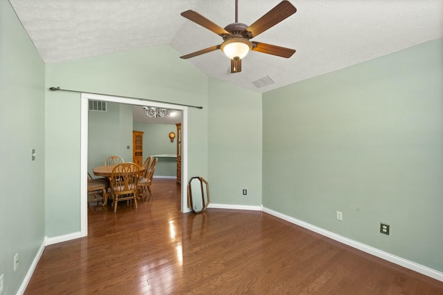 unfurnished room featuring visible vents, vaulted ceiling, baseboards, and wood finished floors