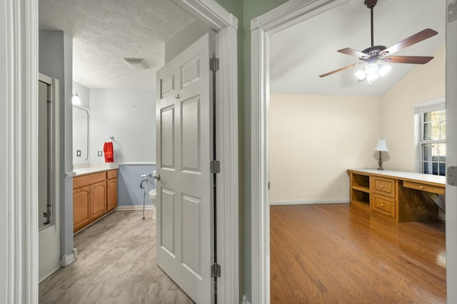 bathroom with toilet, vanity, a textured ceiling, wood finished floors, and baseboards