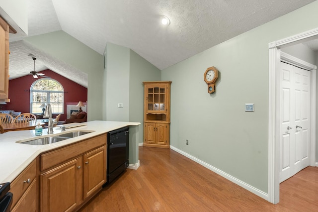 kitchen featuring lofted ceiling, light countertops, dishwasher, and a sink