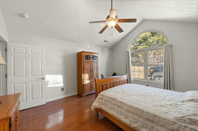 bedroom featuring lofted ceiling, a textured ceiling, wood finished floors, a ceiling fan, and baseboards