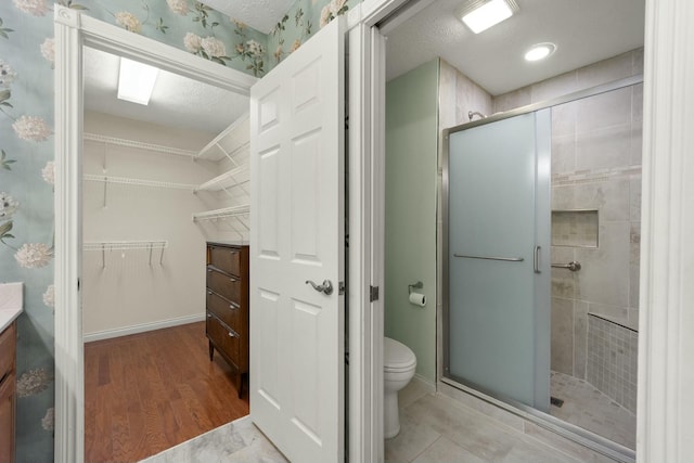 bathroom with a spacious closet, toilet, a textured ceiling, a shower stall, and vanity