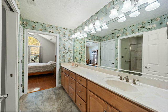 bathroom featuring a sink, wallpapered walls, connected bathroom, and a stall shower