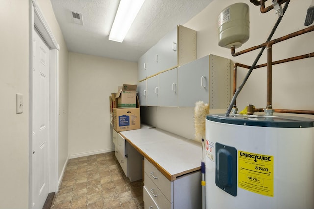 utility room featuring electric water heater and visible vents