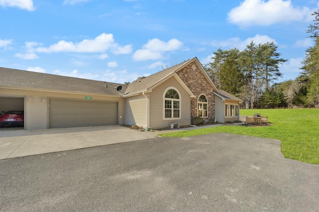 view of front of home with a garage, stone siding, driveway, and a front lawn