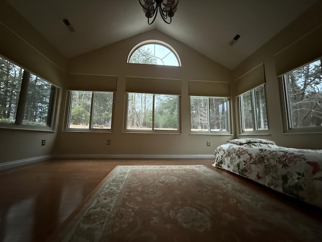 bedroom with visible vents, vaulted ceiling, a notable chandelier, and wood finished floors