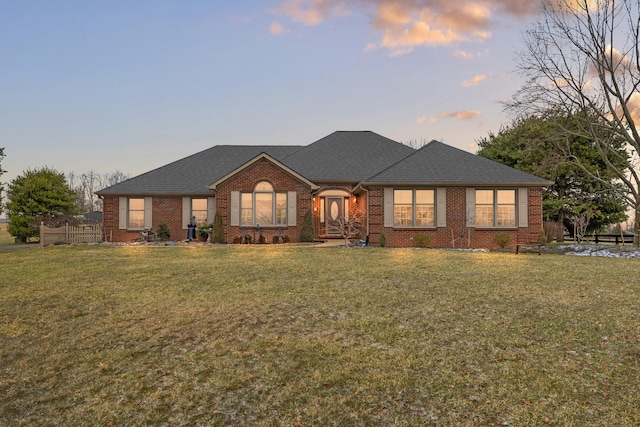 view of front of home with a lawn, brick siding, and a shingled roof