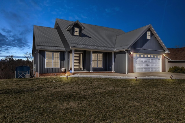 view of front of property featuring board and batten siding, concrete driveway, a front yard, metal roof, and a garage