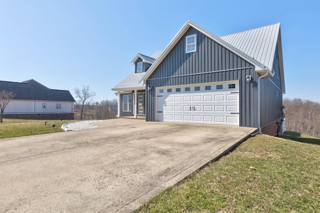 view of front of property with board and batten siding, a front lawn, concrete driveway, metal roof, and an attached garage