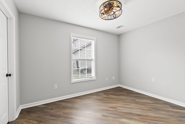 spare room with baseboards, visible vents, and wood finished floors