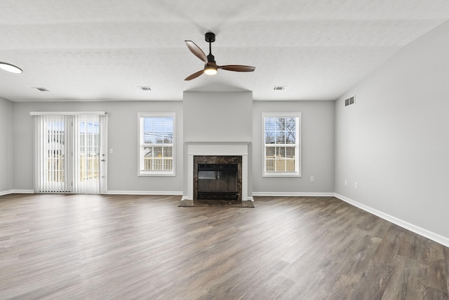 unfurnished living room featuring plenty of natural light, visible vents, and dark wood finished floors