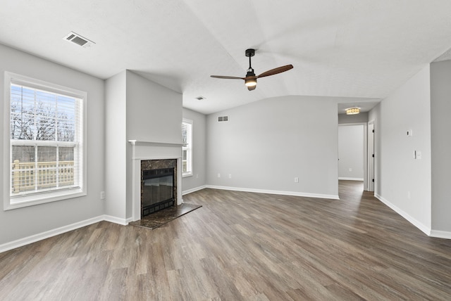 unfurnished living room featuring a wealth of natural light, visible vents, a fireplace, and wood finished floors