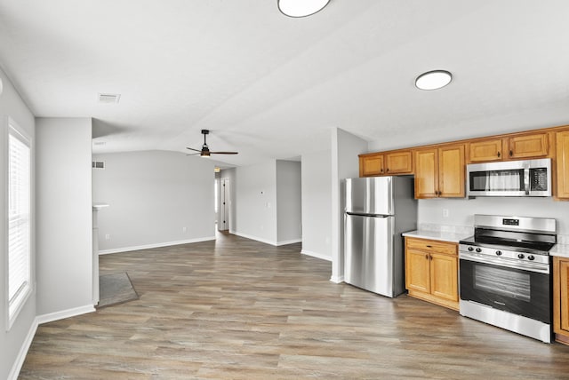 kitchen featuring lofted ceiling, stainless steel appliances, visible vents, light countertops, and light wood-type flooring