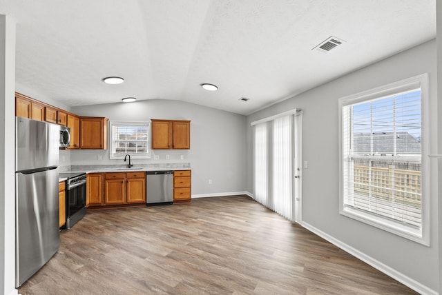 kitchen featuring visible vents, brown cabinetry, stainless steel appliances, light countertops, and a sink