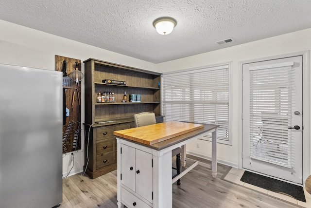 office space featuring a textured ceiling, baseboards, visible vents, and light wood-style floors