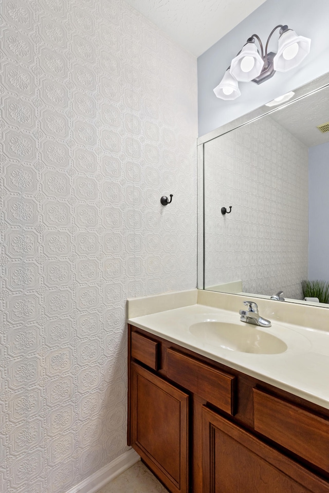 bathroom with wallpapered walls, visible vents, and vanity