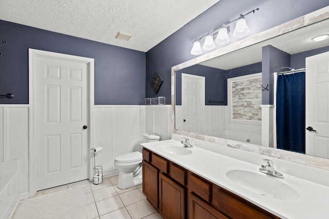 full bath featuring a bathtub, wainscoting, a sink, and a textured ceiling