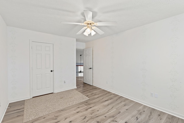 unfurnished room featuring light wood-style floors, a textured ceiling, baseboards, and a ceiling fan