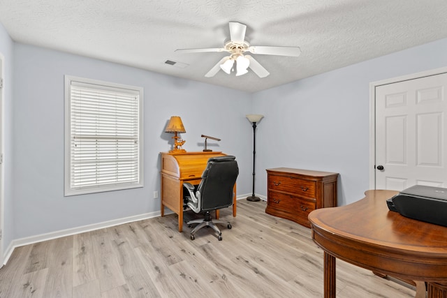 office featuring a textured ceiling, baseboards, a ceiling fan, and light wood-style floors