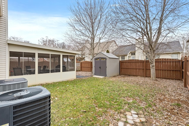 view of yard featuring a storage shed, a sunroom, central AC, a fenced backyard, and an outdoor structure