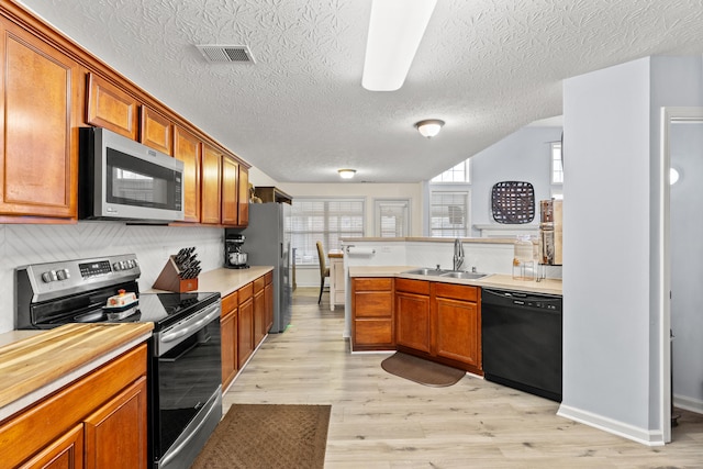 kitchen featuring light wood finished floors, visible vents, appliances with stainless steel finishes, light countertops, and a sink