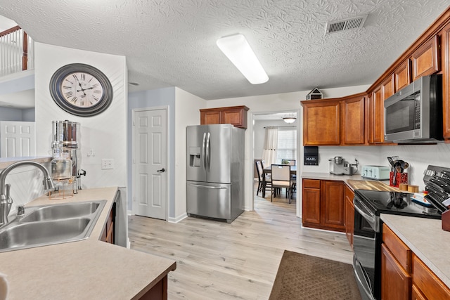 kitchen featuring visible vents, light wood-style flooring, appliances with stainless steel finishes, light countertops, and a sink