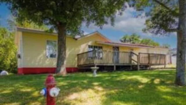 rear view of property featuring a deck and a yard