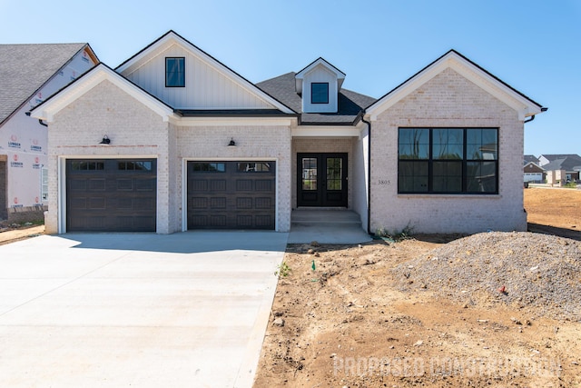 modern inspired farmhouse with an attached garage, brick siding, concrete driveway, french doors, and board and batten siding