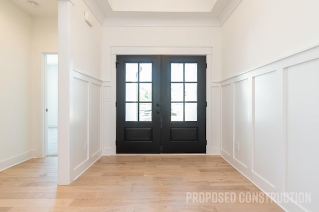 entryway featuring french doors, a decorative wall, and light wood-style flooring