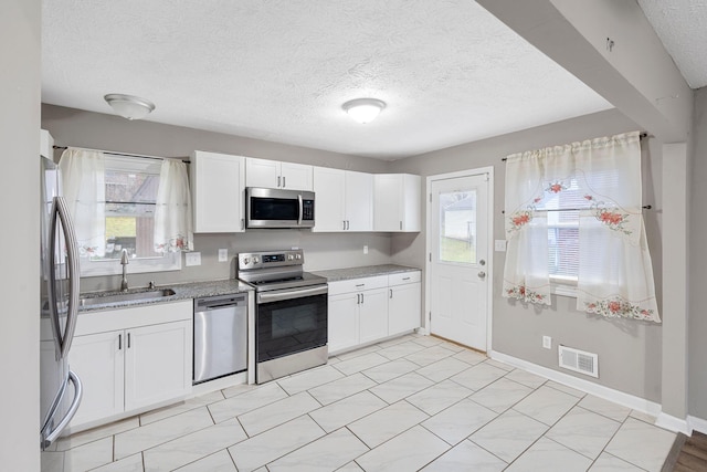 kitchen featuring a sink, visible vents, baseboards, white cabinets, and appliances with stainless steel finishes