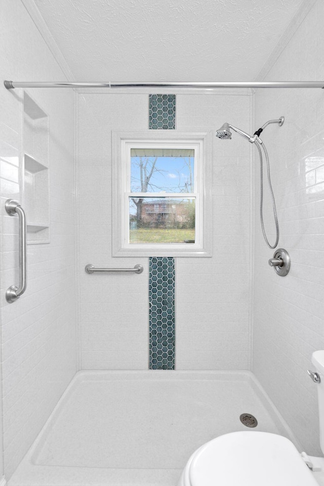 bathroom featuring toilet, a shower stall, and a textured ceiling