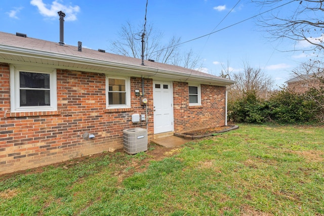 rear view of property featuring a yard, central AC unit, and brick siding