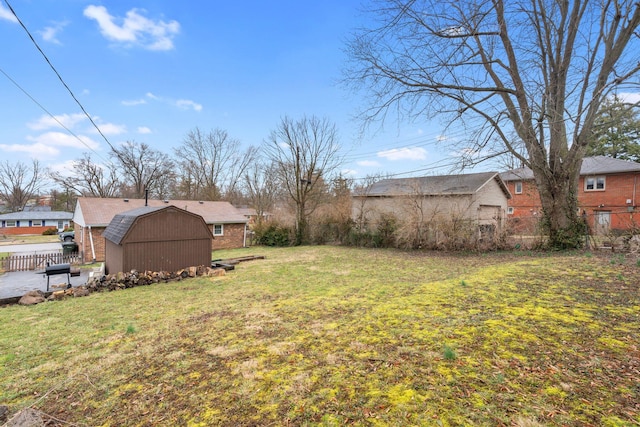 view of yard featuring a storage shed, fence, and an outdoor structure