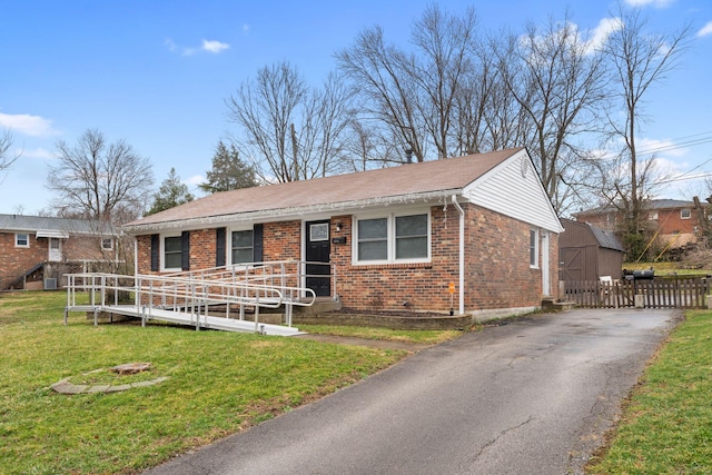 single story home with brick siding, a front lawn, an outdoor structure, and aphalt driveway