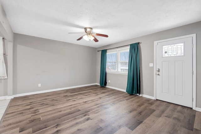 foyer entrance featuring ceiling fan, a textured ceiling, baseboards, and wood finished floors