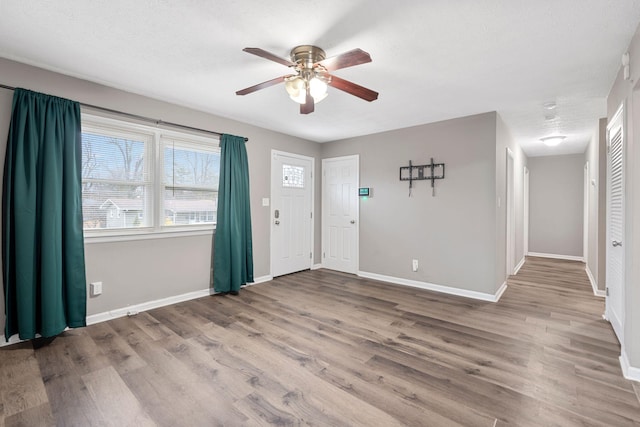 foyer entrance featuring ceiling fan, baseboards, and wood finished floors