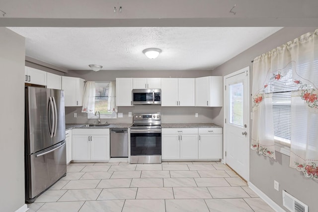 kitchen featuring white cabinetry, visible vents, appliances with stainless steel finishes, and a sink