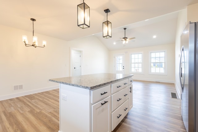 kitchen with visible vents, white cabinets, vaulted ceiling, light wood-style floors, and freestanding refrigerator