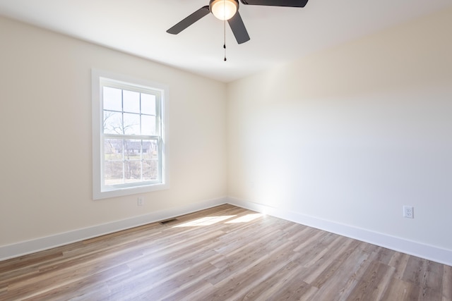 spare room featuring baseboards, visible vents, ceiling fan, and light wood finished floors