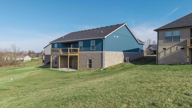 rear view of property with a patio area, brick siding, a yard, and a wooden deck