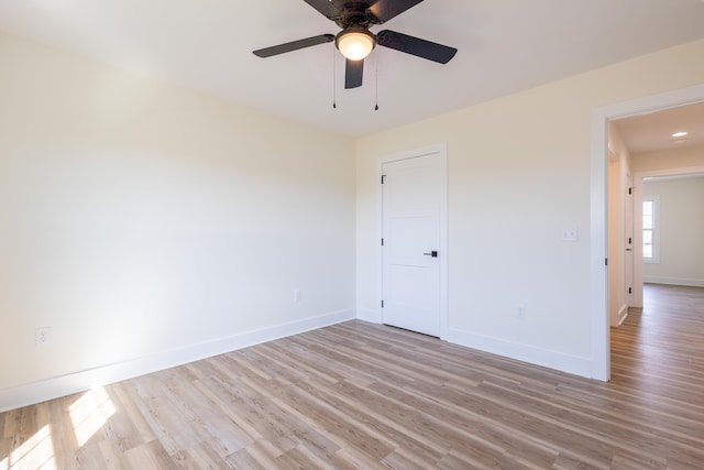 spare room featuring light wood-style floors, ceiling fan, and baseboards